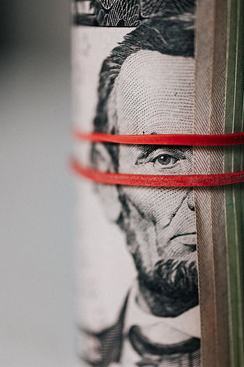 Detailed close-up of rolled US dollar bills secured by a red rubber band emphasizing currency and finance concepts. HD phone wallpaper