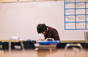 A high school student studying and solving problems in a classroom setting. HD wallpaper