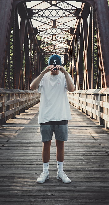 Casual fashion of a man posing on a metal bridge on a sunny day. HD phone wallpaper