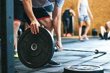 Focused weightlifting session in a gym with diverse athletes participating indoors. HD wallpaper