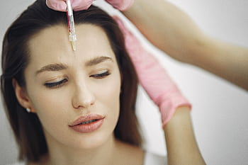 Close-up of facial treatment with injection in a spa setting, focusing on the forehead. HD wallpaper