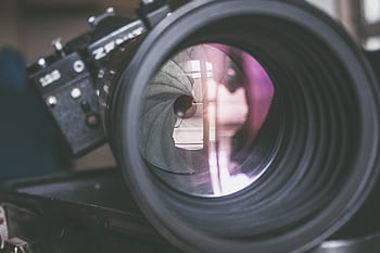 Detailed close-up of a vintage camera lens with visible aperture blades and reflections. HD wallpaper