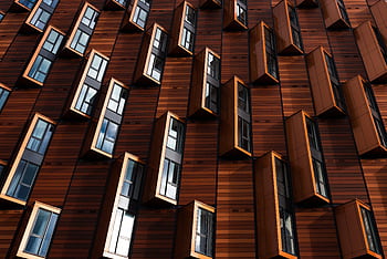 Dynamic pattern of windows in a modern urban facade with geometric designs. HD wallpaper