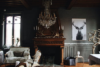 A cozy living room featuring vintage decor with a chandelier, fireplace, and antlers. HD wallpaper