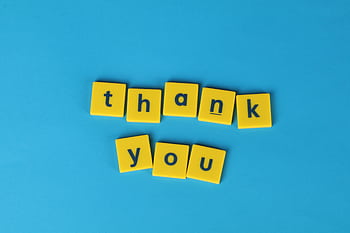 Bright yellow letter tiles spelling 'thank you' on a blue background, perfect for gratitude notes. HD wallpaper
