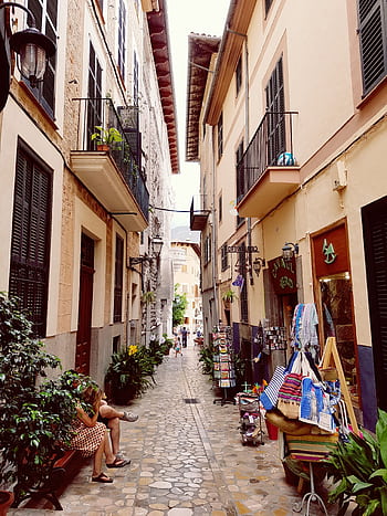 Explore a que narrow street in Madrid lined with quaint shops and balconies. HD phone wallpaper