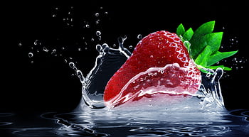 Dynamic shot of a strawberry splashing into water with vivid colors against a black background. HD wallpaper