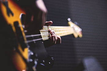 Close-up of a musician strumming an electric bass guitar with focus on fingers. HD wallpaper