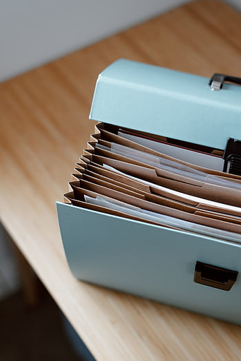 Blue accordion file box on a wooden desk with neatly organized documents. HD phone wallpaper