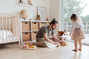 Father engaging with daughter in a playful indoor setting, building memories. HD wallpaper