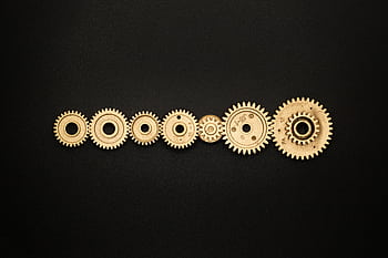 An artistic arrangement of golden gears on a dark backdrop, symbolizing mechanics and cooperation. HD wallpaper