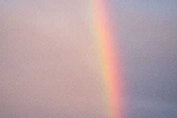 A vivid rainbow stretches across a tranquil cloudy sky, evoking a sense of calm and wonder. HD wallpaper