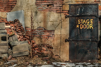 An aged, rustic stage door amidst cracked walls and old bricks in Georgetown, Colorado. HD wallpaper