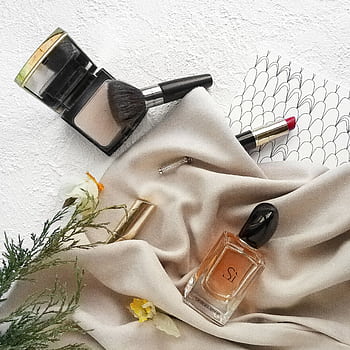 Luxurious flat lay featuring makeup products, perfume, and elegant fabric for a sophisticated feel. HD phone wallpaper