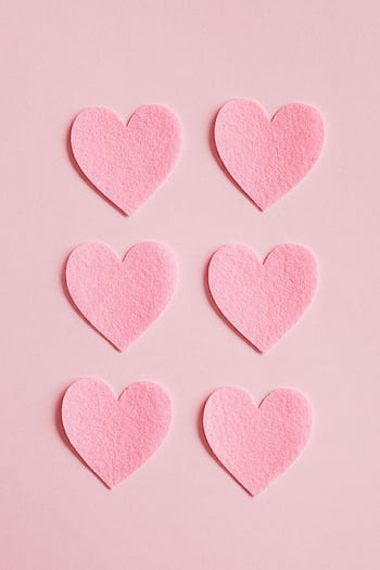 Pink felt heart cutouts arranged on a light pink background, perfect for Valentine's themed designs. HD phone wallpaper