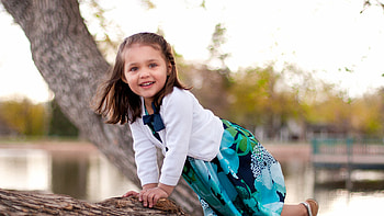 Beautiful Cute Little Girl Is Sitting On Tree Trunk Wearing White Blue Dress In Blur Bokeh Background Cute HD wallpaper