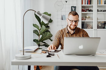 Adult male working remotely in a stylish home office with a laptop, displaying a modern workspace. HD wallpaper