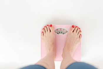 Female feet on a pink scale, highlighting wellness and weight management concepts. HD wallpaper