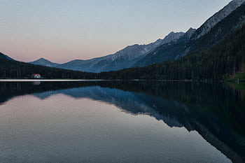 A calm lake reflecting mountains and forests at sunset, perfect for landscape graphy. HD wallpaper