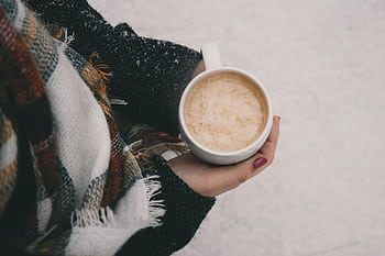 Warm cup of coffee in hands wrapped in a plaid scarf, perfect for a winter chill. HD wallpaper