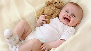 Smiling Cute Baby Toddler Is Lying Down On White Cloth With Teddy Bear Wearing White Dress Cute HD wallpaper