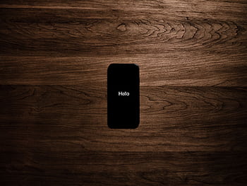 A smart displays 'Hello' against a dark wooden background, offering a sleek tech aesthetic. HD wallpaper