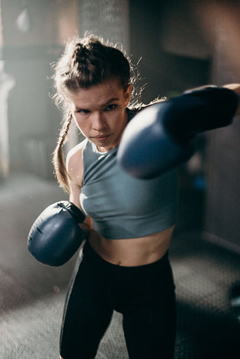 A focused female boxer delivers a powerful punch, showcasing strength and determination. HD phone wallpaper