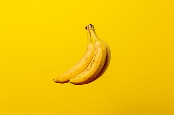 A bunch of ripe yellow bananas against a vivid yellow backdrop, offering tropical freshness. HD wallpaper