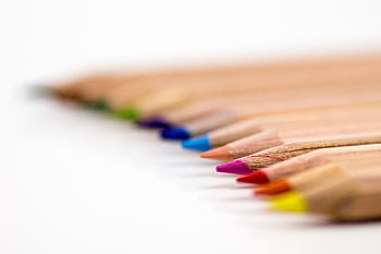 Close-up of colorful pencils aligned on a white surface, showcasing vibrant creativity. HD wallpaper
