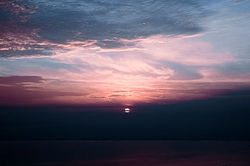 Beautiful sunset scene with clouds and calm ocean waters, showcasing vivid colors in the sky. HD wallpaper