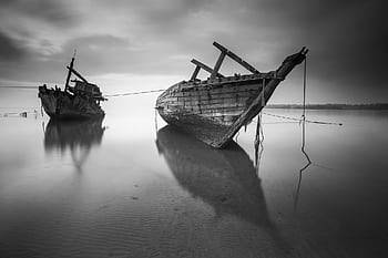 Black and white graph of two shipwrecks on a calm sea shore. HD wallpaper