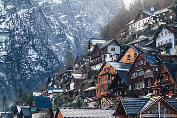 Charming wooden homes nestled on a snowy cliffside in Liezen, Austria, during winter. HD wallpaper