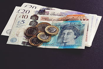 High-quality of British pound notes and coins on a dark surface, showcasing currency detail. HD wallpaper