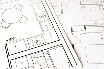 Close-up view of an architectural floor plan on paper showcasing detailed room layouts and measurements. HD wallpaper