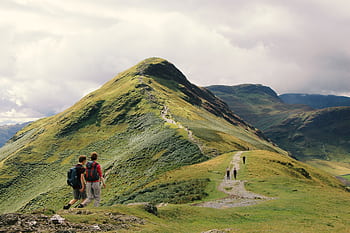 Hikers enjoy a scenic walk along a ridge in the stunning Lake District, England. HD wallpaper