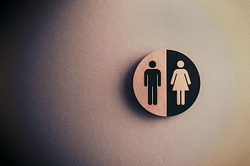 Minimalist gender neutral restroom sign with male and female symbols on textured wall. HD wallpaper