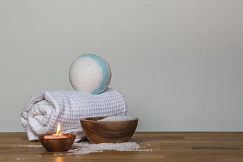 Peaceful spa setting with bath bomb, salt, candle, and towel, perfect for relaxation. HD wallpaper