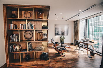 Stylish office space featuring a wooden bookshelf and a minimalist desk setup, ideal for work. HD wallpaper