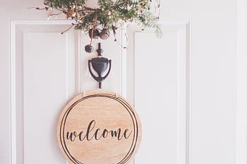 A stylish welcome sign with festive greenery on a door, perfect for home decoration. HD wallpaper