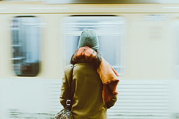 A woman in winter attire waits for a train at a New York subway station. HD wallpaper