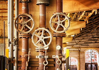 Close-up of rusty industrial pipes and valves, showcasing aging machinery in a factory setting. HD wallpaper