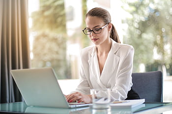 Confident businesswoman using a laptop at her desk, focused on her work. HD wallpaper