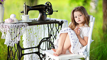 Cute Little Girl Is Sitting On Chair Wearing White Dress In Blur Green Background Near Sewing Machine Cute HD wallpaper