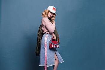 Trendy fashion model poses in a stylish studio setting, showcasing a chic outfit with accessories. HD wallpaper