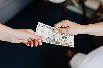 Two people exchanging a ten dollar bill in a close-up hand-to-hand transaction. HD wallpaper