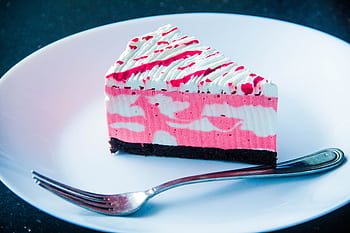 Close-up of a vibrant raspberry cream cake slice with a fork on a plate, perfect for dessert lovers. HD wallpaper