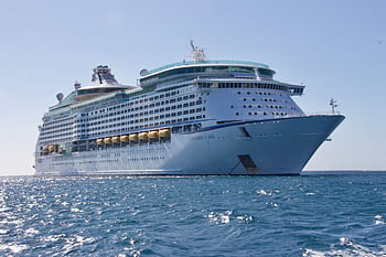 A luxurious cruise ship sailing on the ocean under a clear blue sky, ideal for travel and leisure. HD wallpaper