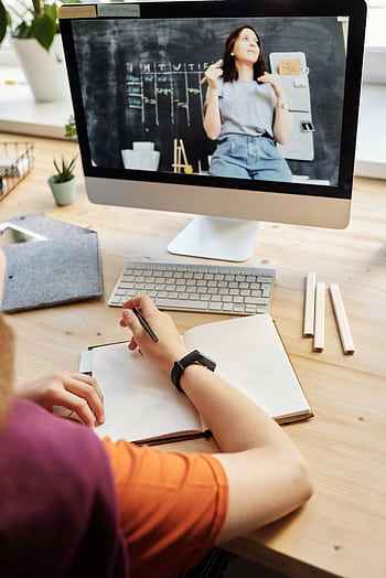 Student attending virtual class on a computer, taking notes at home. HD phone wallpaper