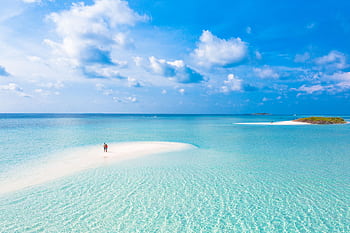 Serene aerial view of a tropical island beach with crystal clear blue waters and white sandy shores. HD wallpaper