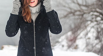 A woman enjoying a snowy winter day, dressed warmly and smiling. HD wallpaper